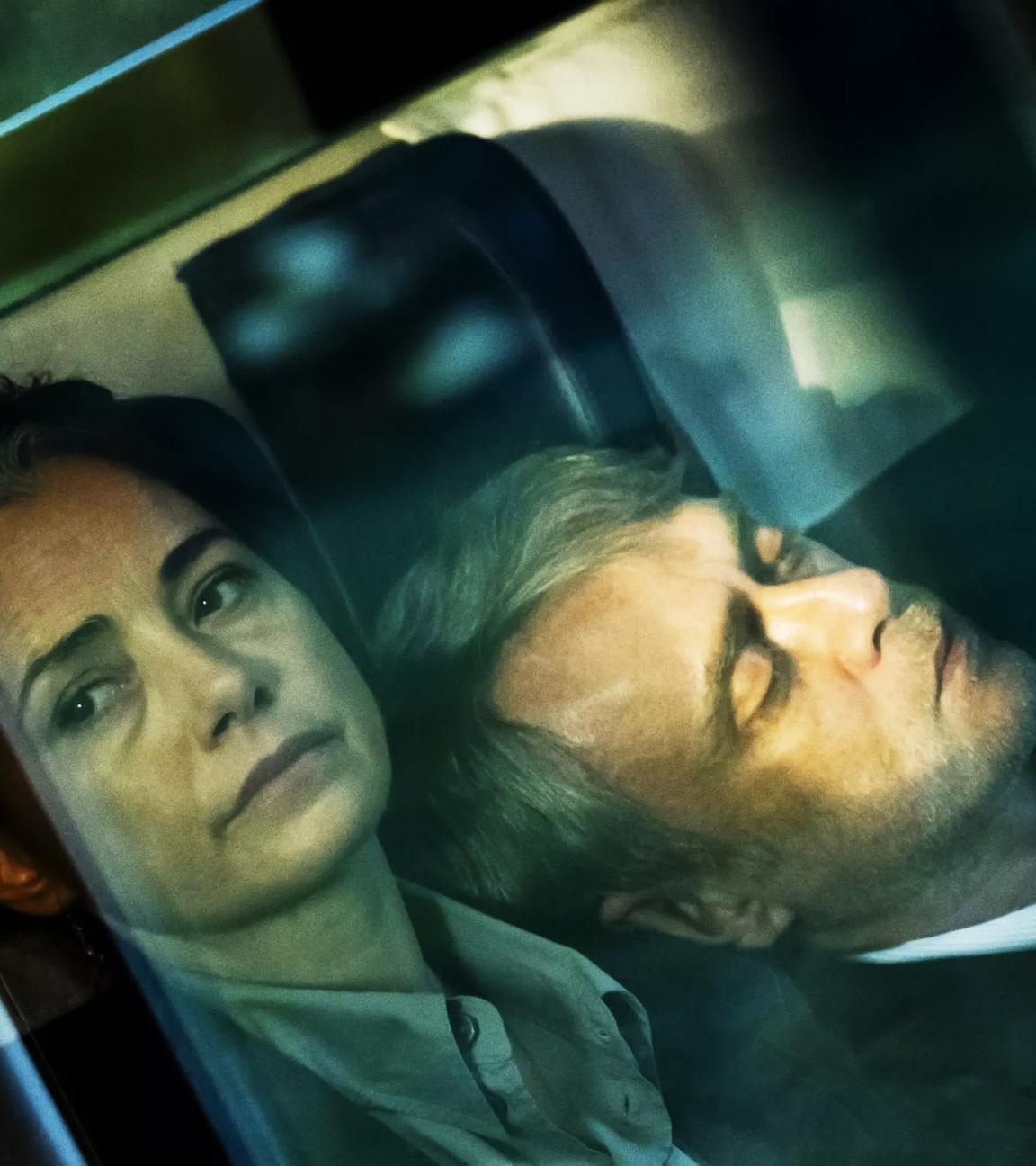 Ein Frau schaut aus einem Zugabteil nach draußen, an ihrer Schulter lehnt ein schlafender Mann.