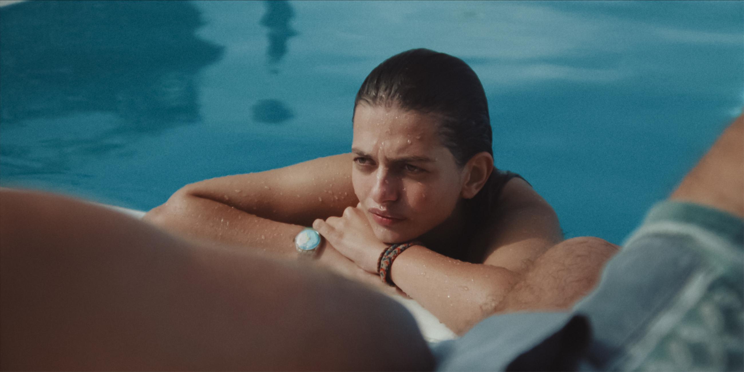 Eine junge Frau ist in einem Pool am Beckenrand.