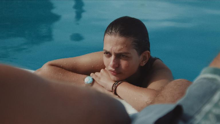 Eine junge Frau ist in einem Pool am Beckenrand.