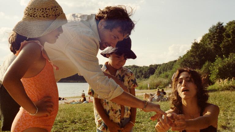 Man sieht eine Frau, einen Mann und zwei Kinder an einem See.