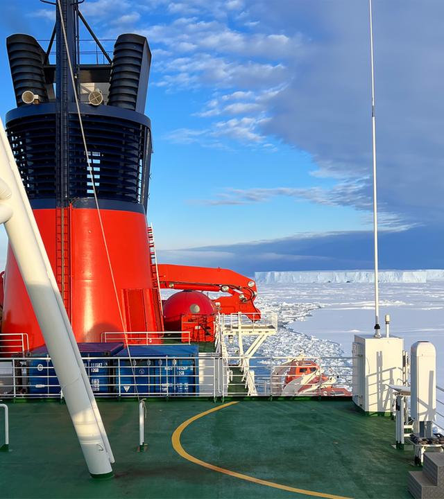 Blick von einem Eisbrecher auf das Polarmeer, auf dem eine Eisschicht liegt.