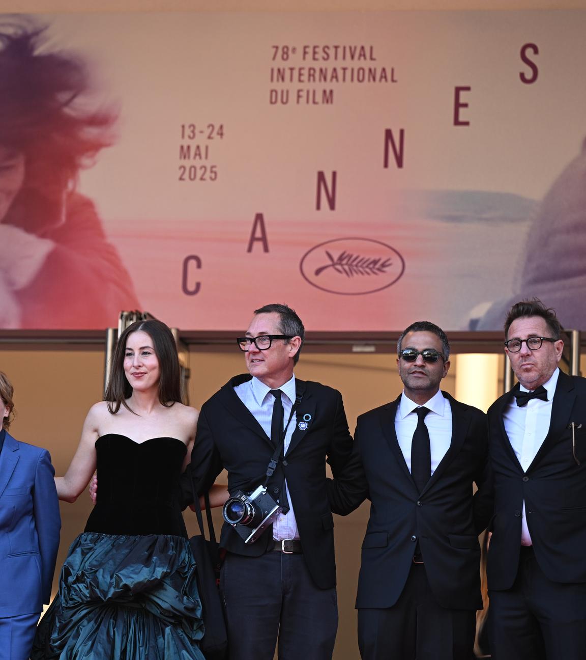 Mehrere Personen der Filmbranche stehen vor einem Plakat der Cannes Filmfestspiele