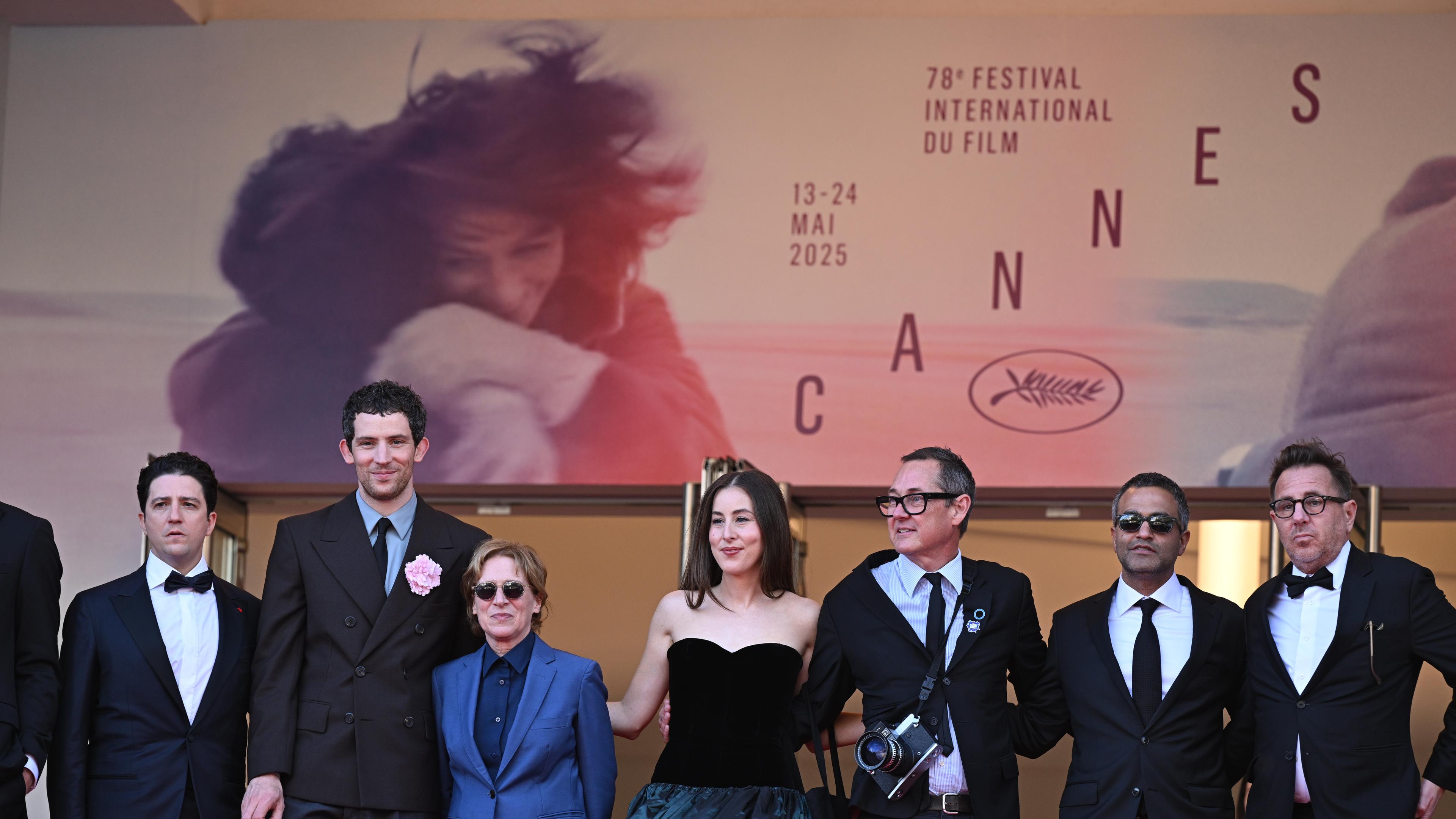 Mehrere Personen der Filmbranche stehen vor einem Plakat der Cannes Filmfestspiele