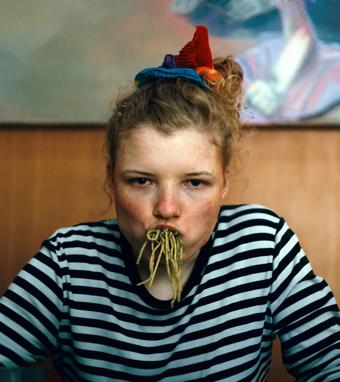 Eine junge Frau hat sich den Mund mit Spaghetti vollgestopft und blickt grimmig in die Kamera.