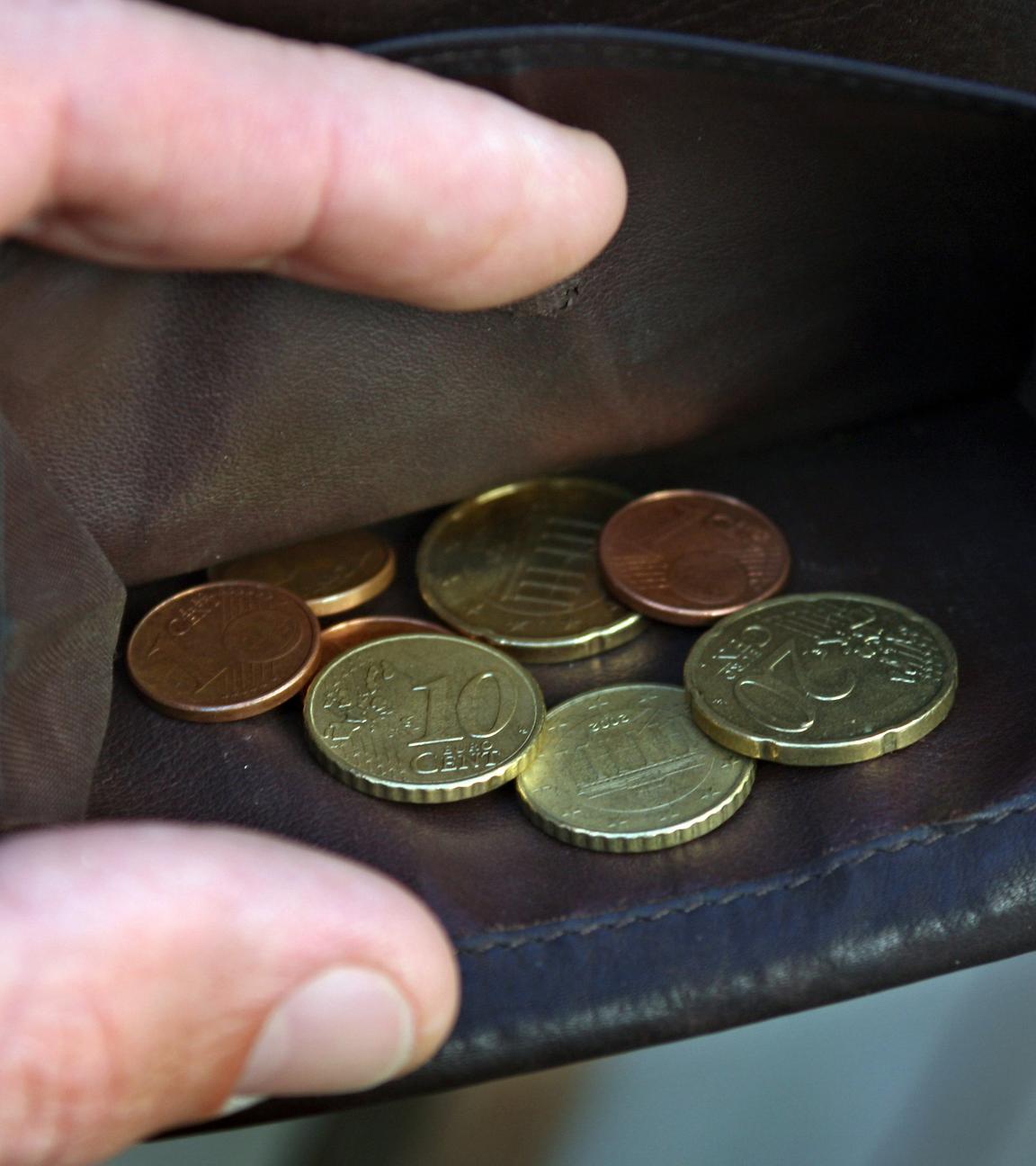 Wenige Euro-Münzen liegen in einem Geldbeutel aus Leder