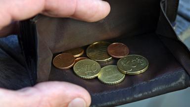 Wenige Euro-Münzen liegen in einem Geldbeutel aus Leder
