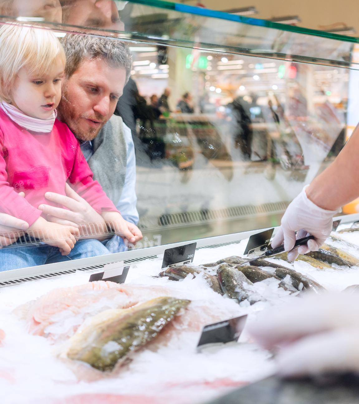 Ein Vater mit Kind an der Fischtheke im Supermarkt