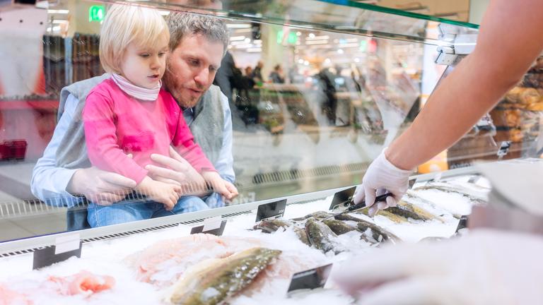 Ein Vater mit Kind an der Fischtheke im Supermarkt