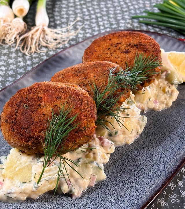 Fischfrikadellen auf Kartoffel-Gurken-Salat serviert.