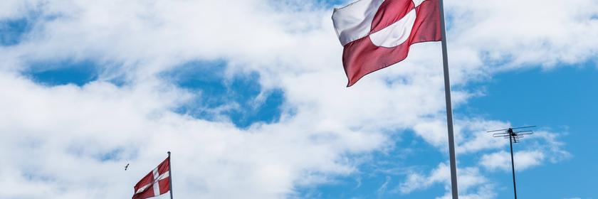 Die dänische und grönländische Flagge weht bei blauem Himmel in Grönland.