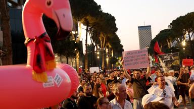 People demonstrate holding an inflatable flamingo and placards in front of Albania's Prime Minister's office against a planned resort linked to US President's family, in Tirana on June 27, 2026. Since late May, protesters have gathered every evening to oppose the construction of a luxury hotel linked to Trump's daughter Ivanka and her husband Jared Kushner, planned in a nature reserve on the Balkan nation's coast.