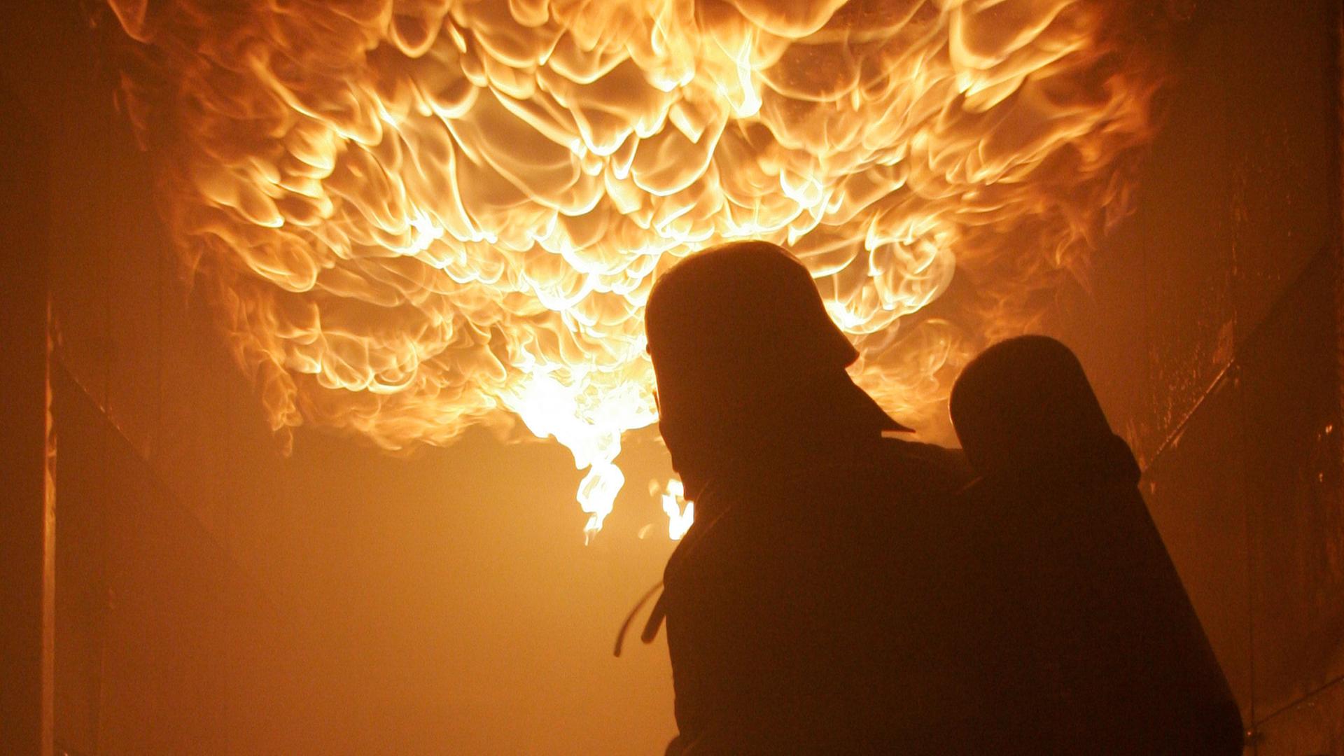 Ein Feuerwehrmann steht unter einer brennenden Decke, um eine Atemschutzschulung in einem gasbefeuerten Brandsimulationssystem, am 18.02.2008 durchzuführen.