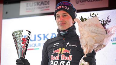 Florian Lipowitz bei der Siegerehrung der Baskenland-Rundfahrt mit einem Pokal in der rechten und einen Blumenstrauß in der linken Hand.