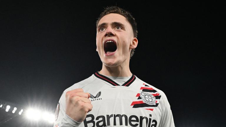 Ein Mann mit kurzen braunen Haaren in einem weißen Trikot und weißer kurzer Hose jubelt. Er hat die Faust geballt und den Mund weit aufgerissen. 