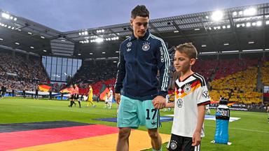 Fußballer Florian Wirtz kommt mit einem Einlaufkind am 31.05.2026 im Freundschafts-Länderspiel gegen Dänemark in die Mewa-Arena in Mainz.