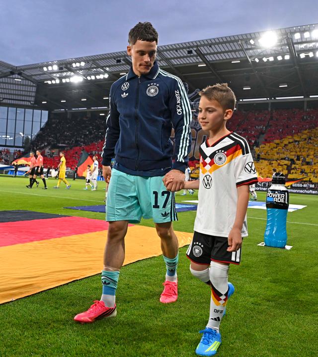 Fußballer Florian Wirtz kommt mit einem Einlaufkind am 31.05.2026 im Freundschafts-Länderspiel gegen Dänemark in die Mewa-Arena in Mainz.
