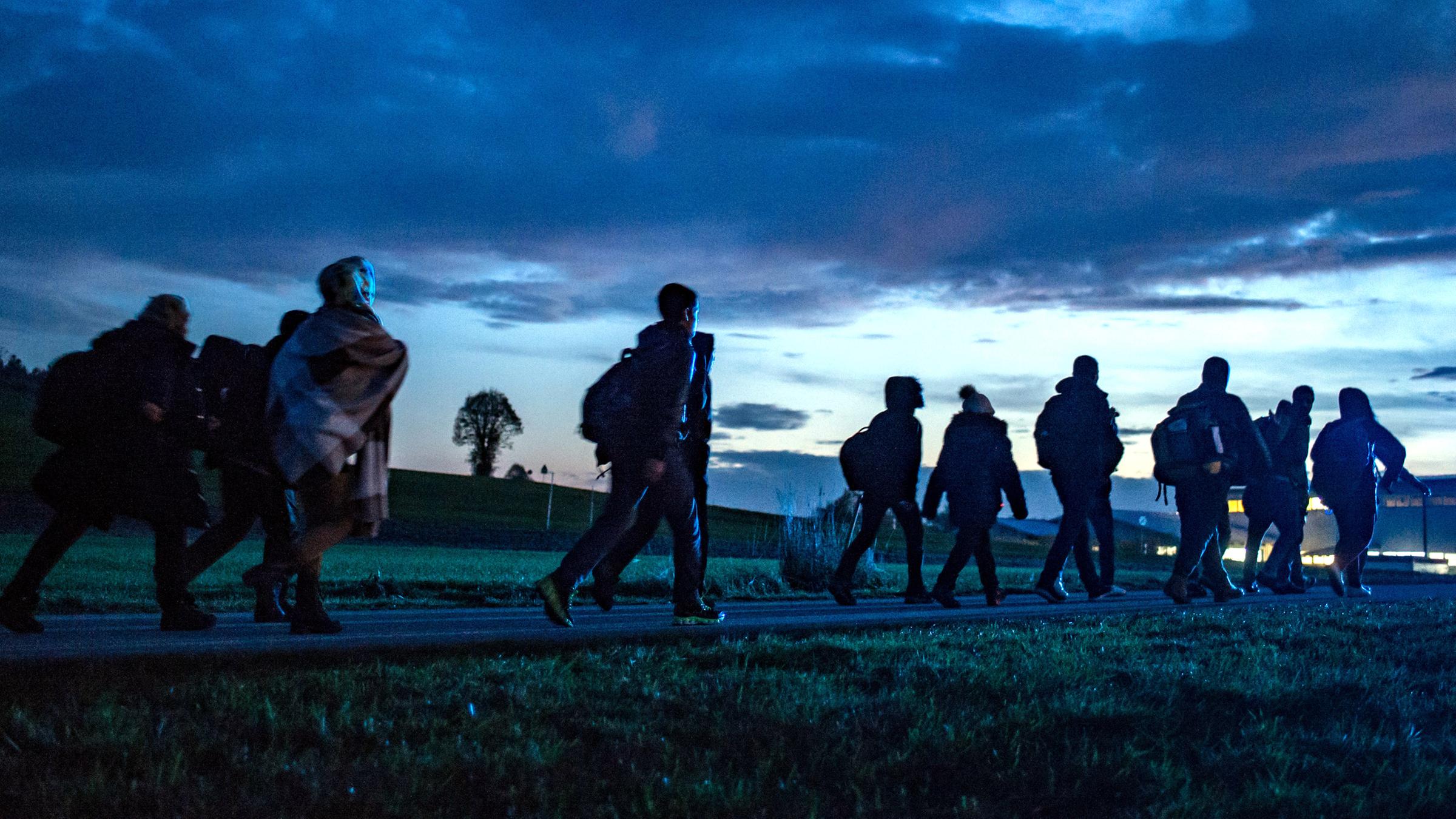 Archiv: Flüchtlinge gehen am 28.10.2015 hinter der deutsch-österreichischen Grenze in Wegscheid (Bayern) zu einer Notunterkunft