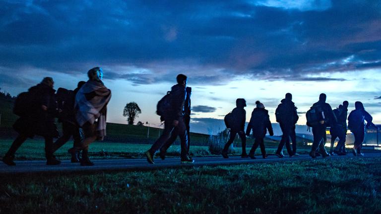 Archiv: Flüchtlinge gehen am 28.10.2015 hinter der deutsch-österreichischen Grenze in Wegscheid (Bayern) zu einer Notunterkunft