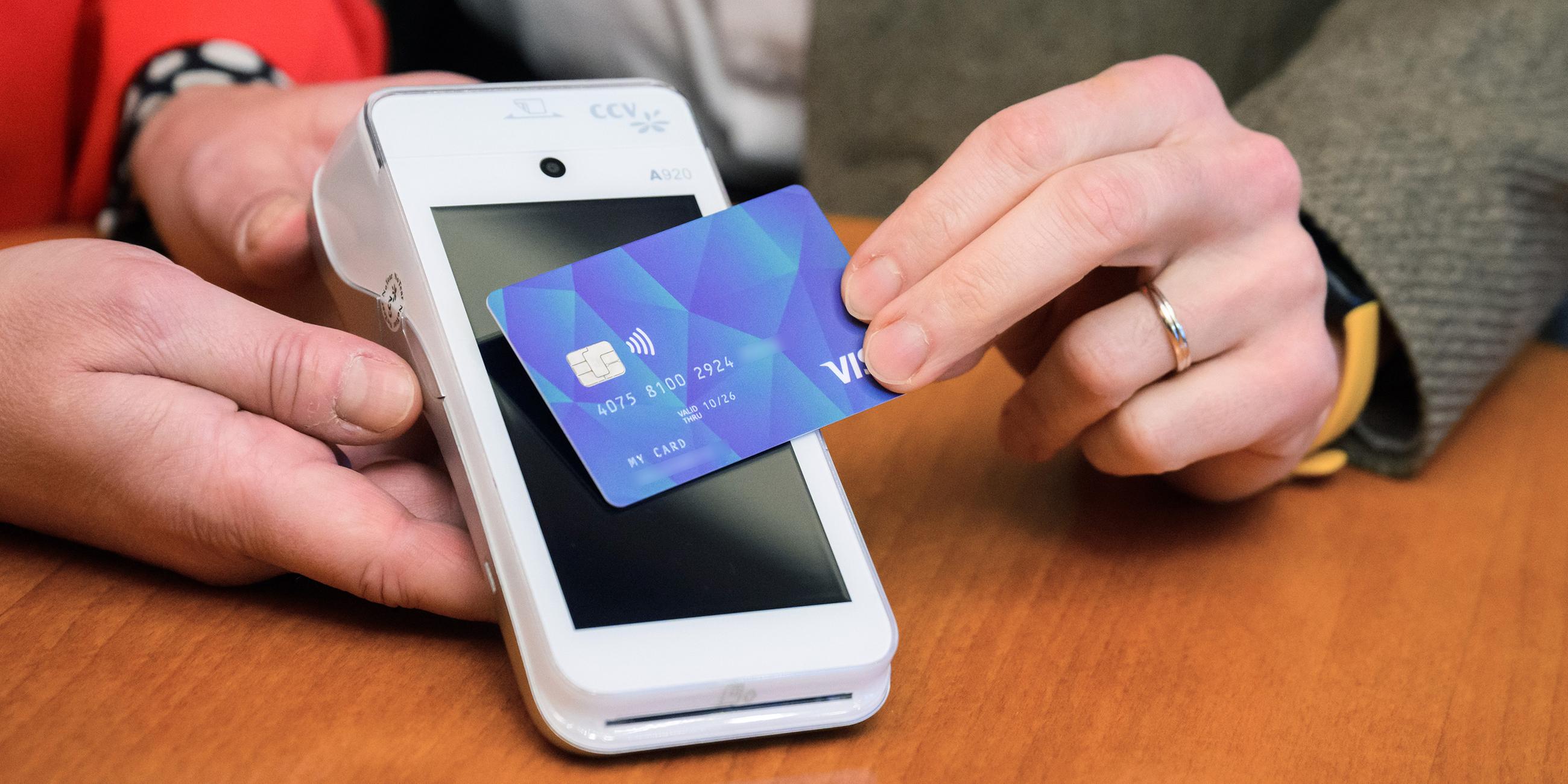 VISA-Debit Karte wird vor ein Lesegerät gehalten
