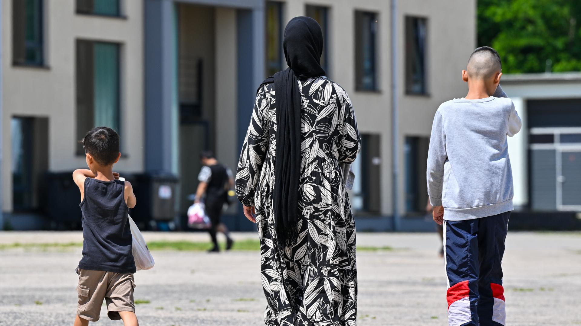 Eine Migrantin und ihre zwei Kinder gehen über das Gelände der Zentralen Erstaufnahmeeinrichtung für Asylbewerber (ZABH) des Landes Brandenburg.