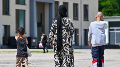 Eine Migrantin und ihre zwei Kinder gehen über das Gelände der Zentralen Erstaufnahmeeinrichtung für Asylbewerber (ZABH) des Landes Brandenburg.
