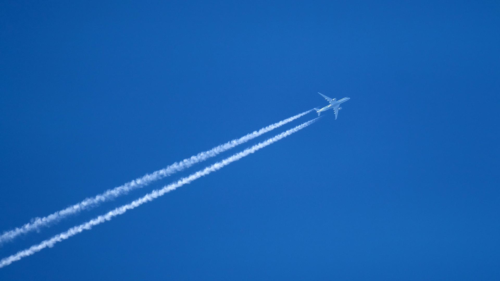 Flugzeug hinterlässt Kondensstreifen am Himmel.