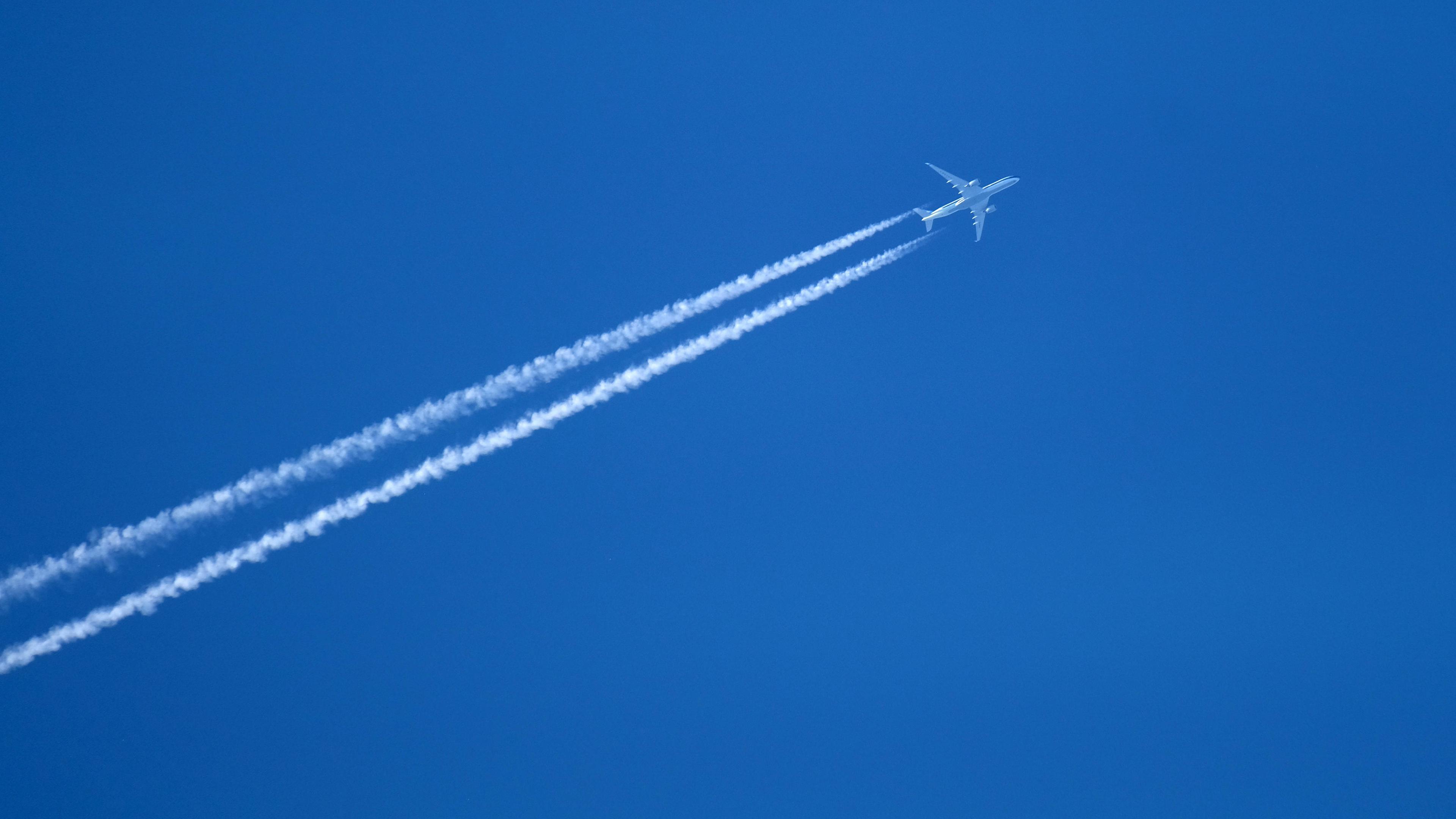 Flugzeug hinterlässt Kondensstreifen am Himmel.