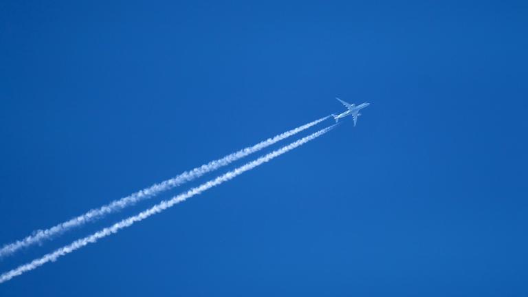 Flugzeug hinterlässt Kondensstreifen am Himmel.
