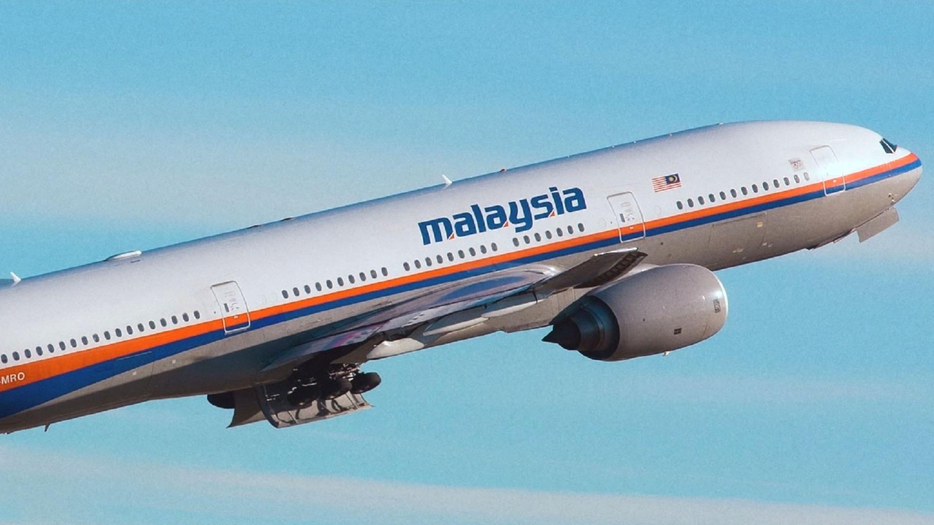 Ein startendes Flugzeug der Malaysian Airlines: Es trägt in blau den Schriftzug Malaysia über den Fenstern, darunter verläuft ein orangefarbener und ein blauer Streifen.