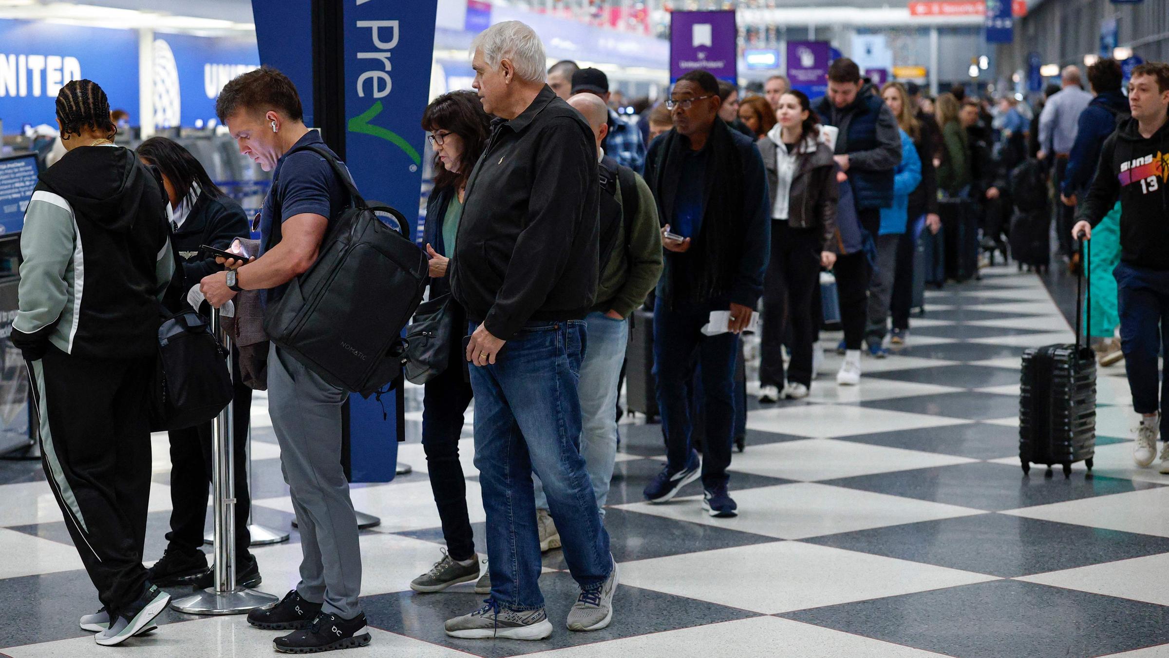 Reisende warten am 7. November 2025 in einer Schlange an einer Sicherheitskontrolle am O'Hare International Airport in Chicago, Illinois. 