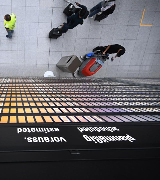 Fluggäste stehen unter einer Anzeigentafel im Terminal 2 des Flughafens in München am 07.06.2025.