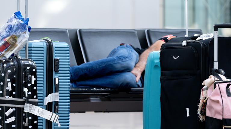 (Symbolbild) Ein Passagiert wartet am Flughafen auf einer Bank auf den weiterflug.