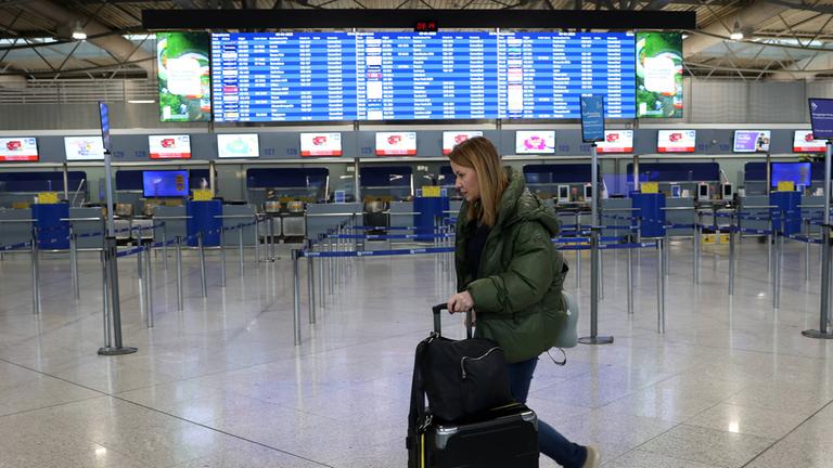 Eine Frau eilt durch den leeren Flughafen in Athen. (Archiv)