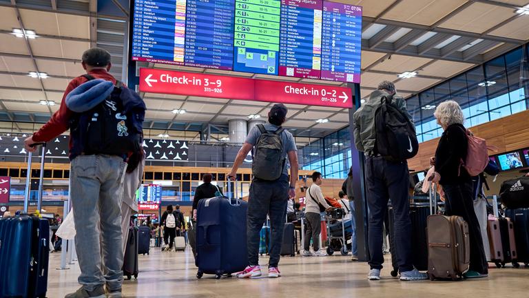 Fluggäste informieren sich an den Abflugtafeln im Terminal 1 des Flughafens Berlin-Brandenburg