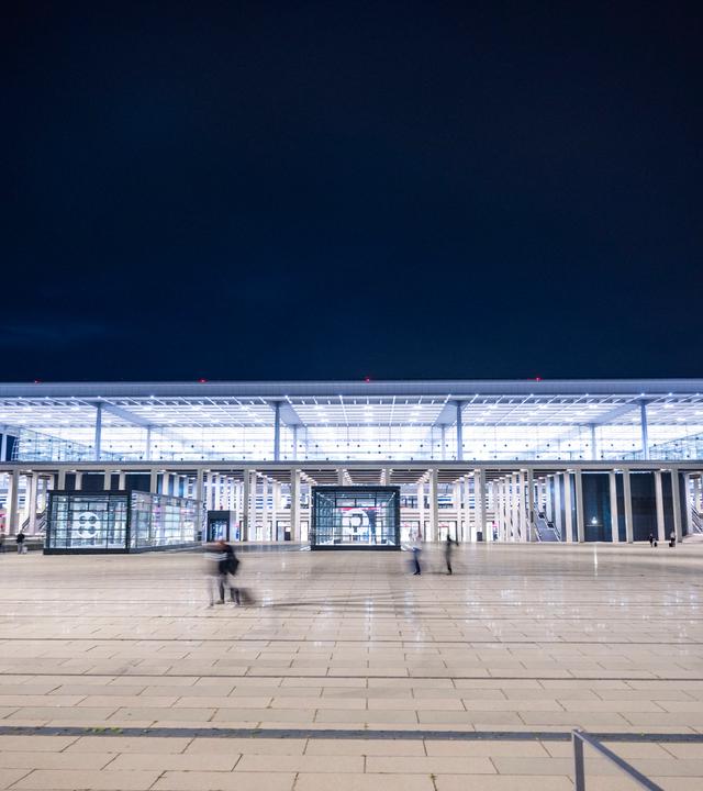 3.09.2026, Brandenburg, Schönefeld: Menschen gehen vor dem Flughafen Berlin-Brandenburg (BER). Wegen einer Drohnensichtung am Hauptstadtflughafen Berlin-Brandenburg (BER) ist der Flugbetrieb am Abend vorübergehend eingestellt worden. 