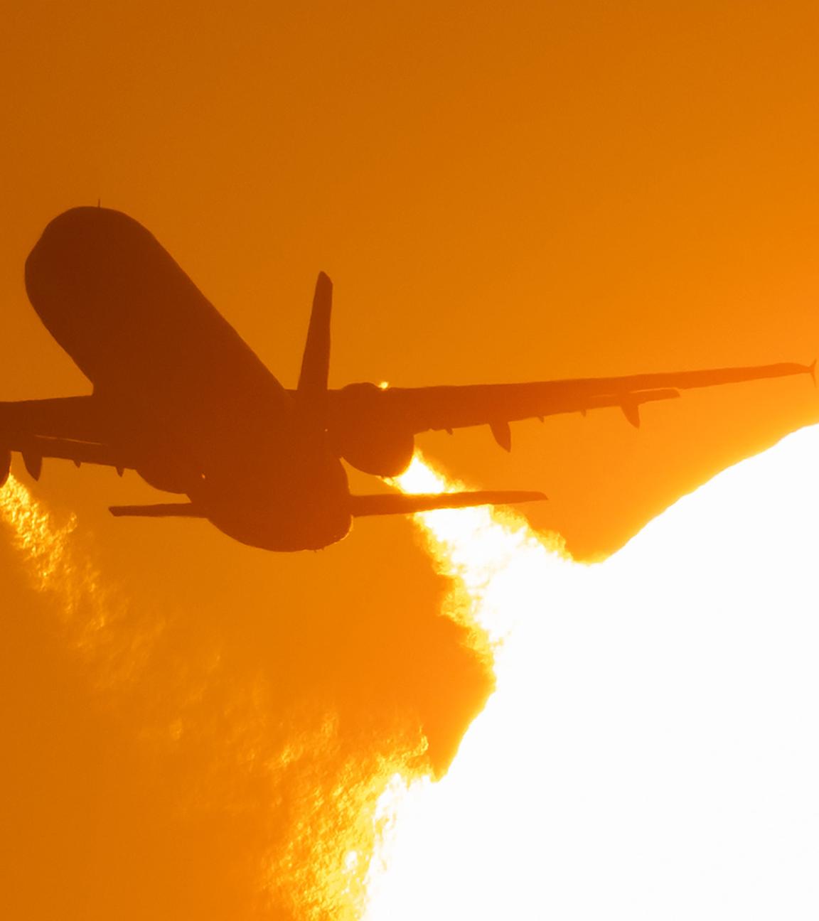 (Archiv) Ein Flugzeug startet vom Flughafen Frankfurt und fliegt dabei an der untergehenden Sonne vorbei.