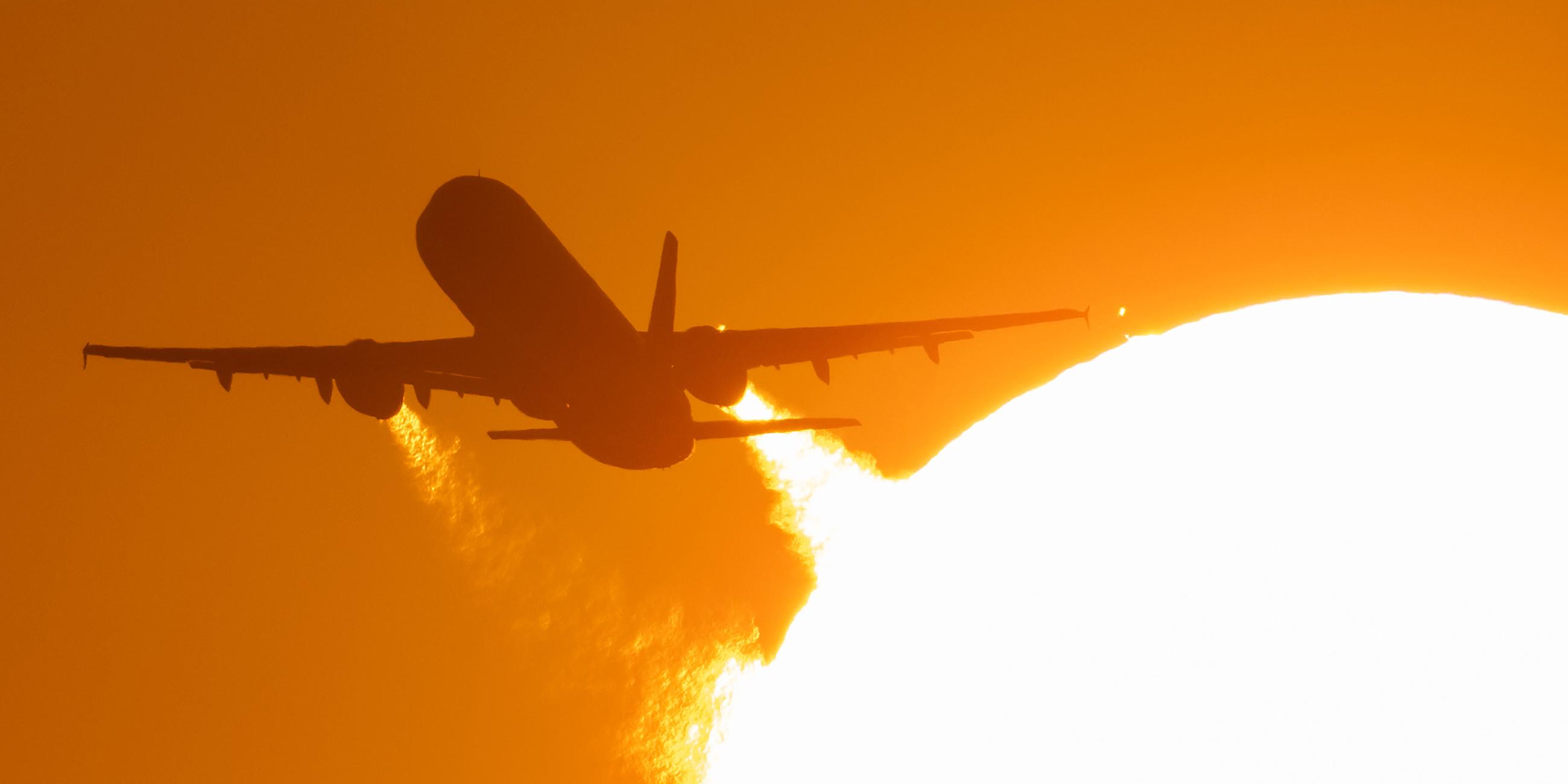 (Archiv) Ein Flugzeug startet vom Flughafen Frankfurt und fliegt dabei an der untergehenden Sonne vorbei.
