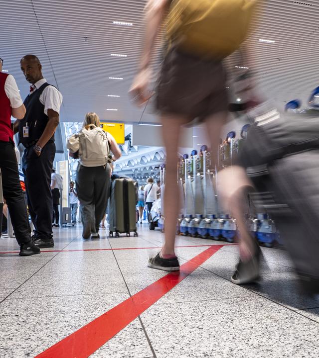 Ein Hund steht mit seinen Besitzern in einer langen Schlange im Terminal 1 des Rheinmain-Flughafens an.