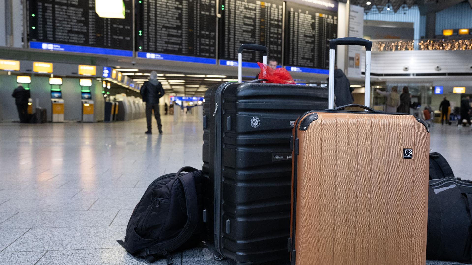 Koffer von Passagieren stehen vor der Anzeigetafel in der Abflughalle des Flughafens in Frankfurt am Main.