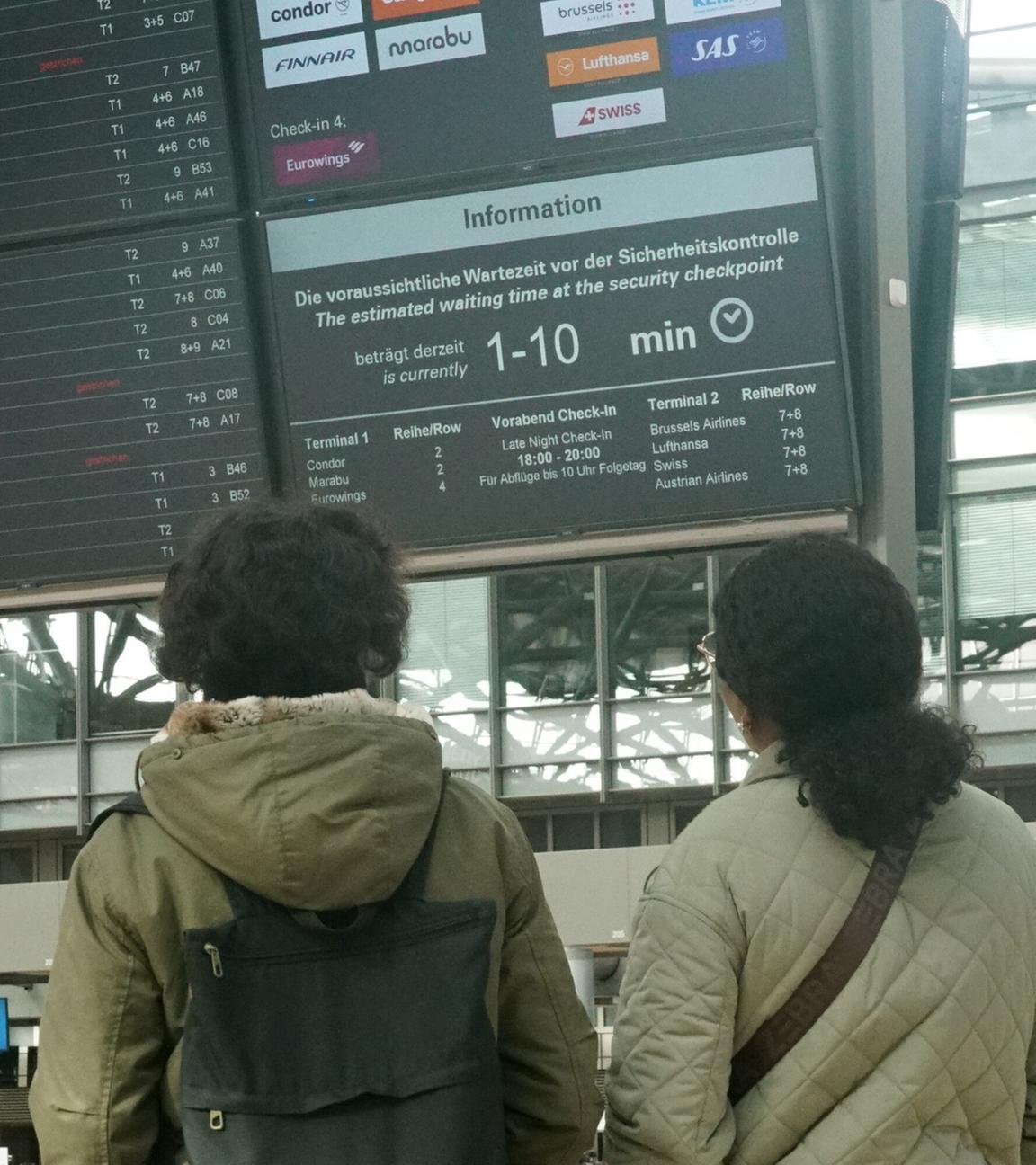 Reisende schauen am 12.03.2026 auf die Fluganzeige am Hamburger Flughafen.