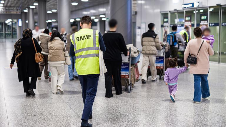 Niedersachsen, Langenhagen: Menschen aus Afghanistan, die zuvor mit einem Flugzeug auf dem Flughafen Hannover-Langenhagen gelandet sind, werden von einem Mitarbeiter des Bundesamtes für Migration und Flüchtlinge (BAMF) durch den Flughafen begleitet.