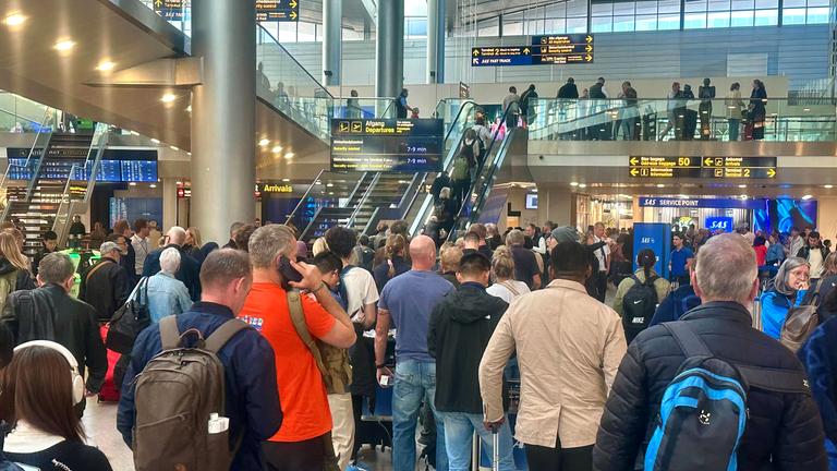 Reisende warten am Flughafen in Kopenhagen an einem Service-Schalter