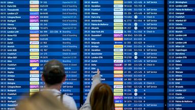 Menschen schauen auf die Abflugtafel am Flughafen