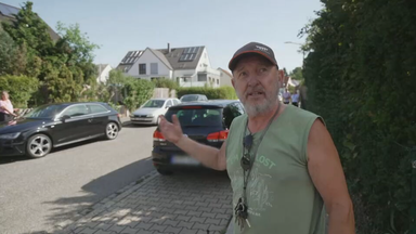 Das Bild zeigt einen männlichen Anwohner, der auf die Parksituation in einer Straße zeigt.