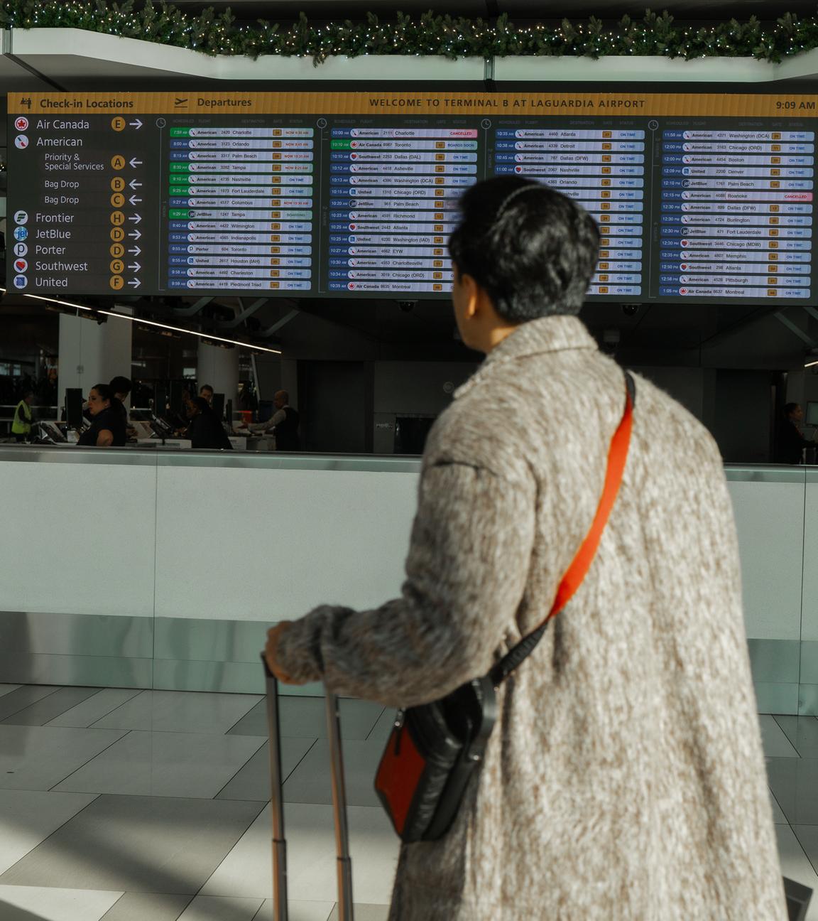 Ein Reisender sieht sich am Samstag, 8. November 2025, den Flugplan am LaGuardia International Airport in New York an.