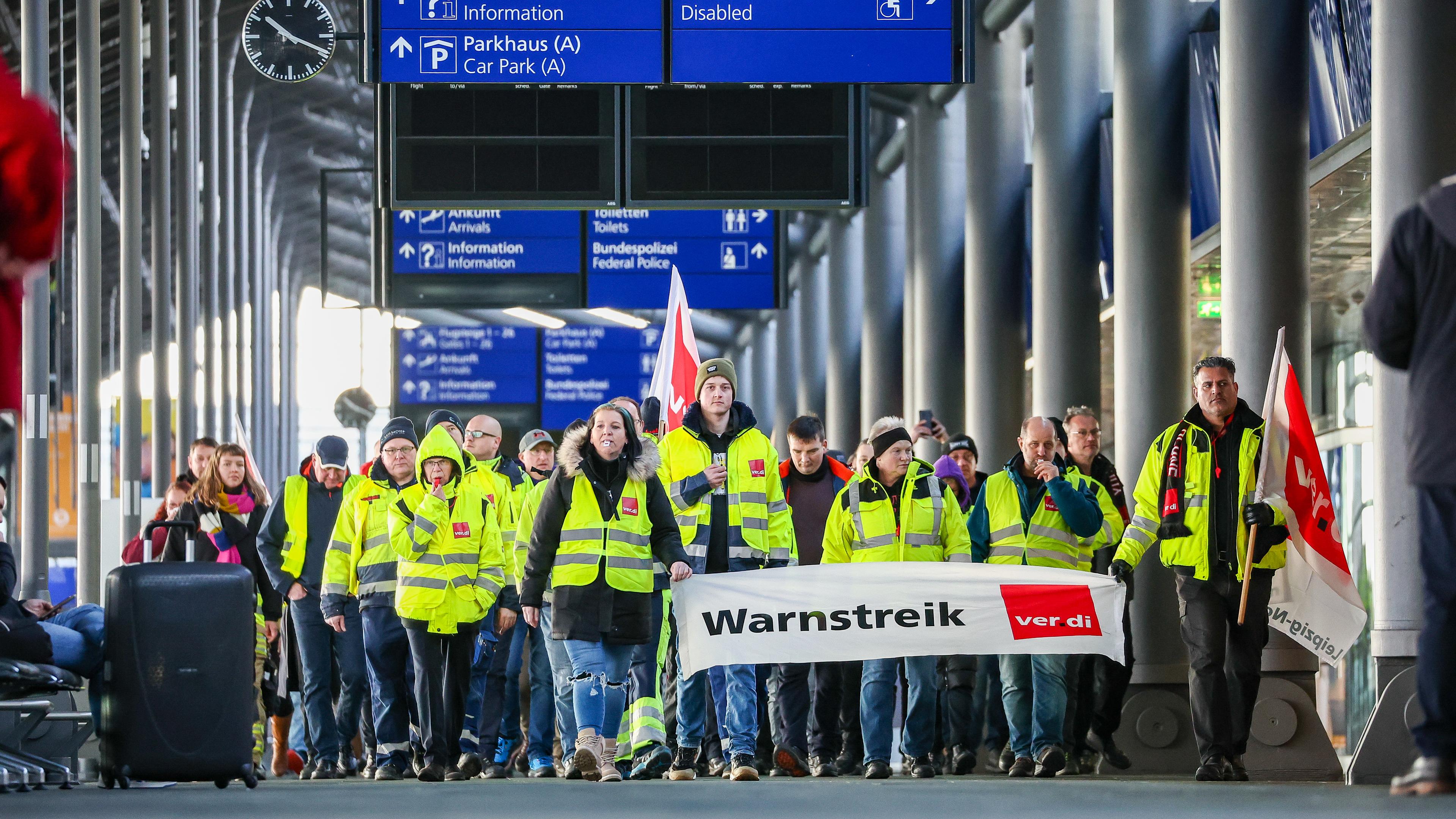 Sachsen, Schkeuditz: Beschäftigte der Mitteldeutschen Flughafen AG gehen während eines Warnstreiks durch den Flughafen Leipzig/Halle.