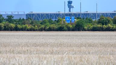 25.08.2026, Sachsen-Anhalt, Kabelsketal: Blick über ein abgeerntetes Feld bei Kabelsketal zum Flughafen Leipzig/Halle. Kanzler Merz (CDU) hat angekündigt, dass sich die Bundesregierung demnächst zu Erkenntnissen über die Urheber des Vorfalls mit einer Sprengstoff-Drohne auf dem Flughafen Leipzig/Halle am 4. August äußern will.