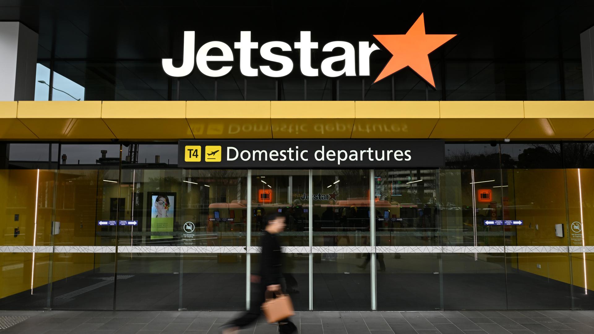 Symbolbild: Eine Person geht vor der Beschilderung für das Jetstar Domestic Abflugterminal am Flughafen Melbourne. 