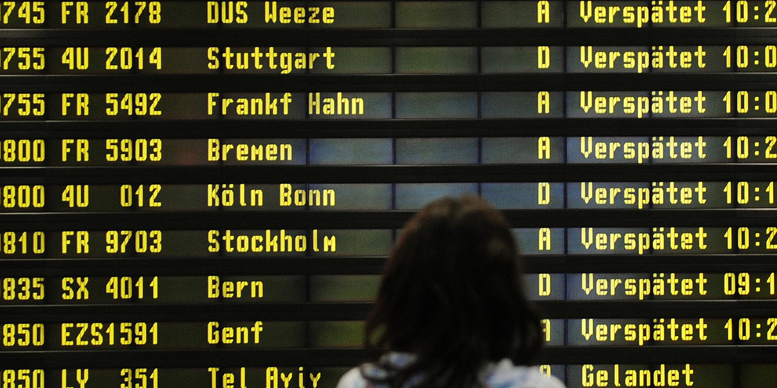 Archiv: Eine Frau steht am 10.12.2010 auf dem Flughafen Berlin-Schönefeld vor einer Anzeigetafel