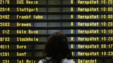 Archiv: Eine Frau steht am 10.12.2010 auf dem Flughafen Berlin-Schönefeld vor einer Anzeigetafel